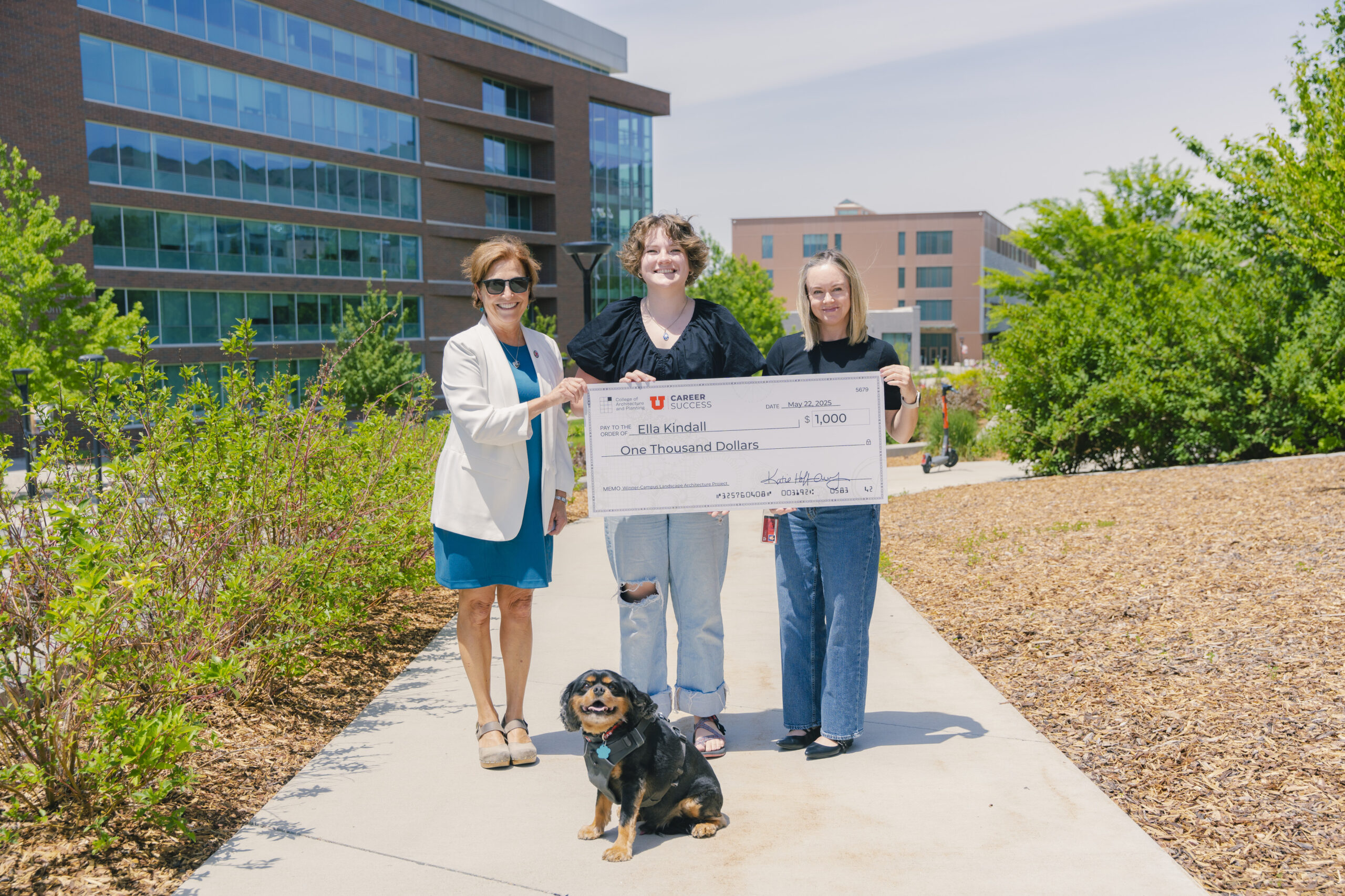 (From left to right) Katie Hoffman-Abby, Landscape Design Winner Ella Kindall, College of Architecture + Planning Career Coach Jana Loftin, and Rocky smile for a photo in front of the Landscape Design location next to the Robert H. and Katharine B. Garff Building at the University of Utah. Ella Kindall holds up a check highlighting the cash prize of $1,000. (From left to right) Katie Hoffman-Abby, Landscape Design Winner Ella Kindall, College of Architecture + Planning Career Coach Jana Loftin, and Rocky smile for a photo in front of the Landscape Design location next to the Robert H. and Katharine B. Garff Building at the University of Utah. Ella Kindall holds up a check highlighting the cash prize of $1,000.